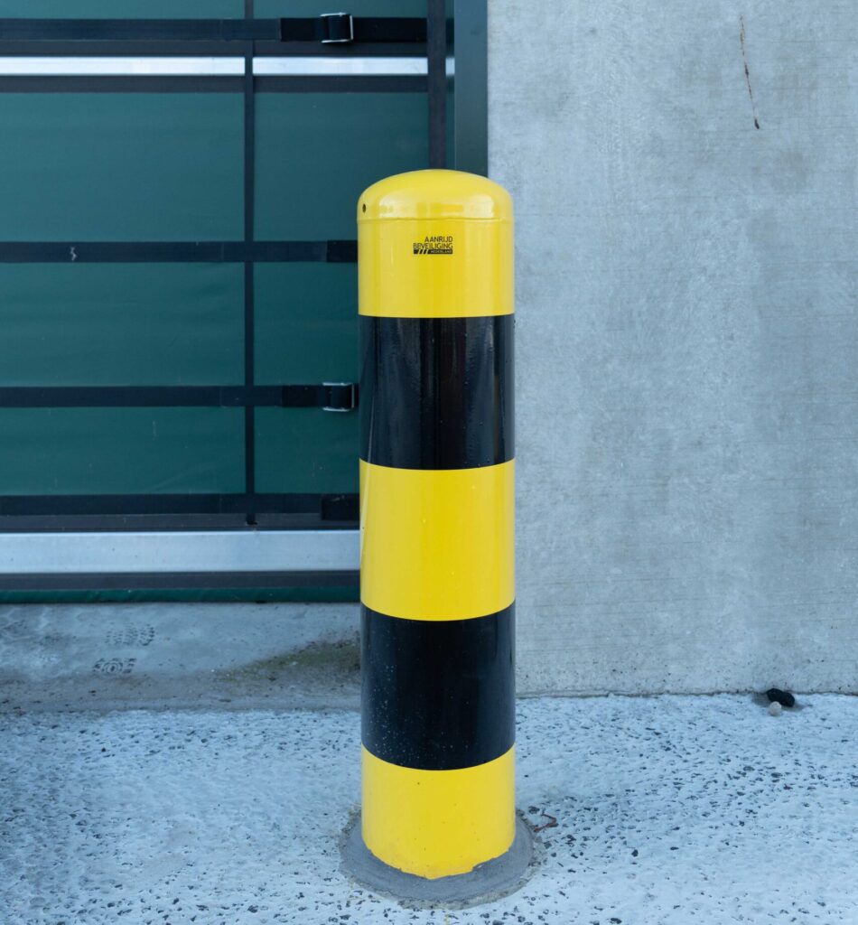 Geel-zwarte rampaal geplaatst als opvallende aanrijdbeveiliging bij bedrijfslocatie